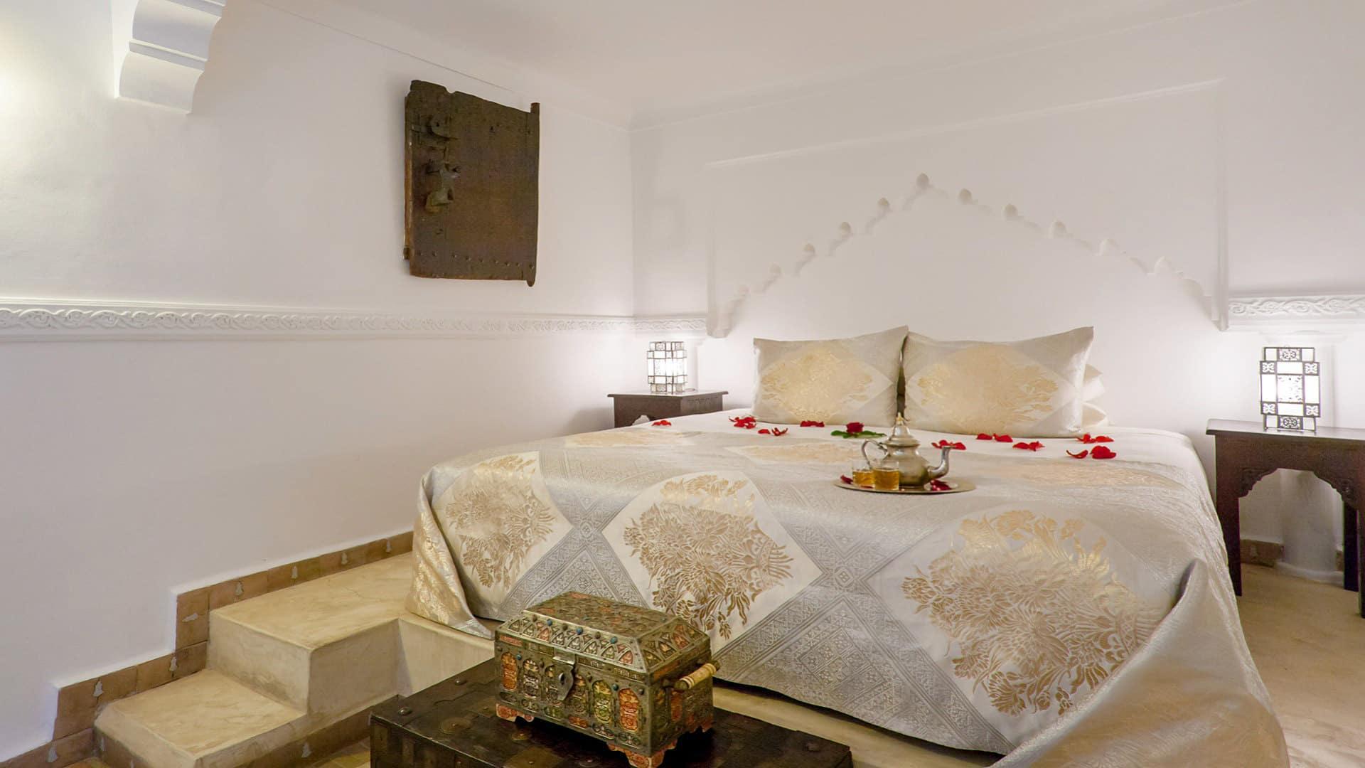 Luxurious bed adorned with rose petals and tea set in Angsana Riads Collection - Marrakech room, Firdaus Deluxe King.