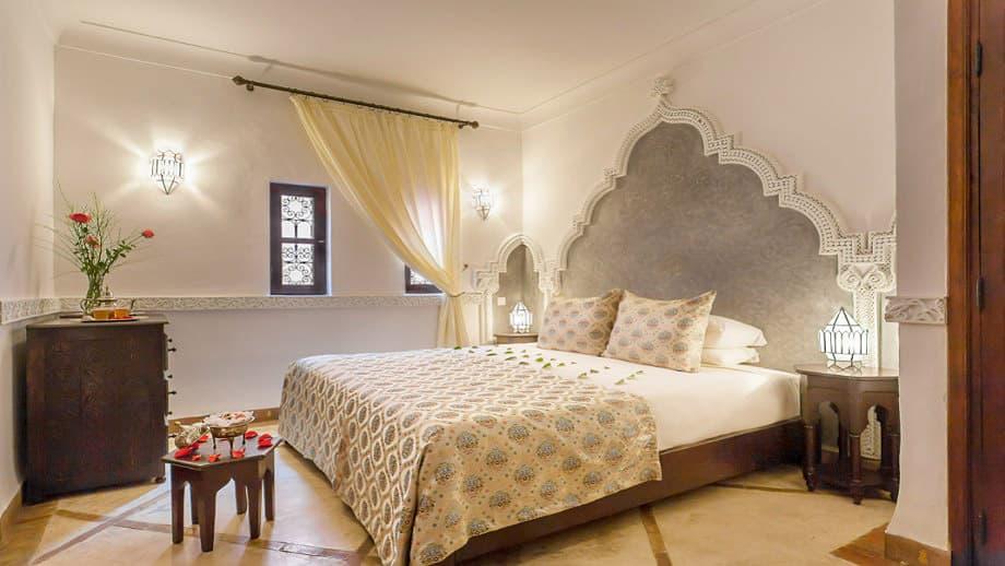 Elegant room features a large bed with ornate headboard, soft lighting, at Angsana Riads Collection - Marrakech, Firdaus Studio King.